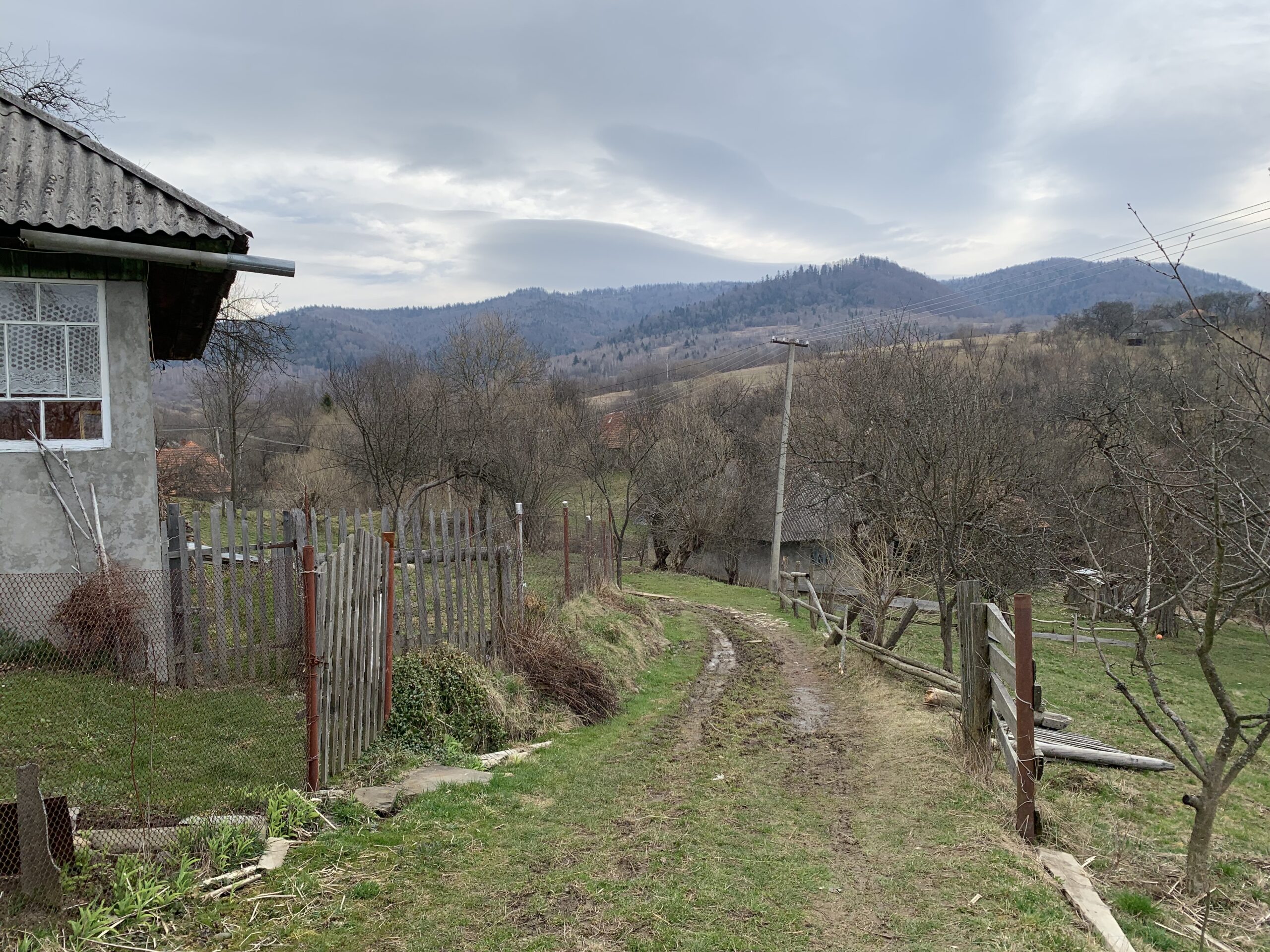 A partial view of a building with a long road heading towards the mountains.